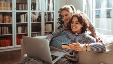 Young lesbian couple online shopping from a laptop on the couch at home